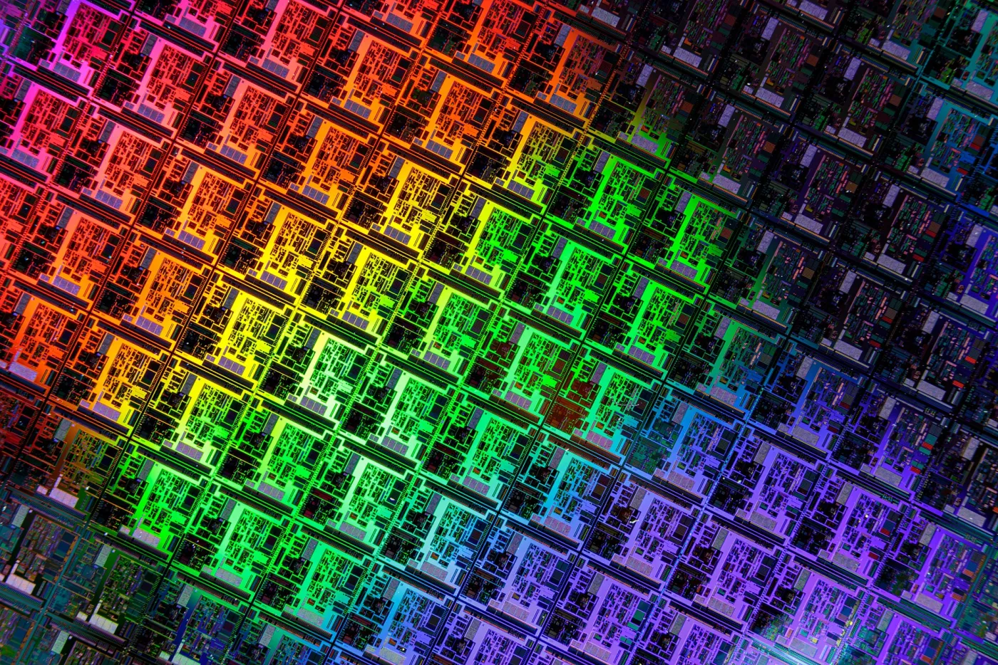 Close-upfoto van een ronde silicium halfgeleiderwafer, waarvan het spiegelende oppervlak glanst met regenboogkleuren door de gepatroneerde schakelingen.